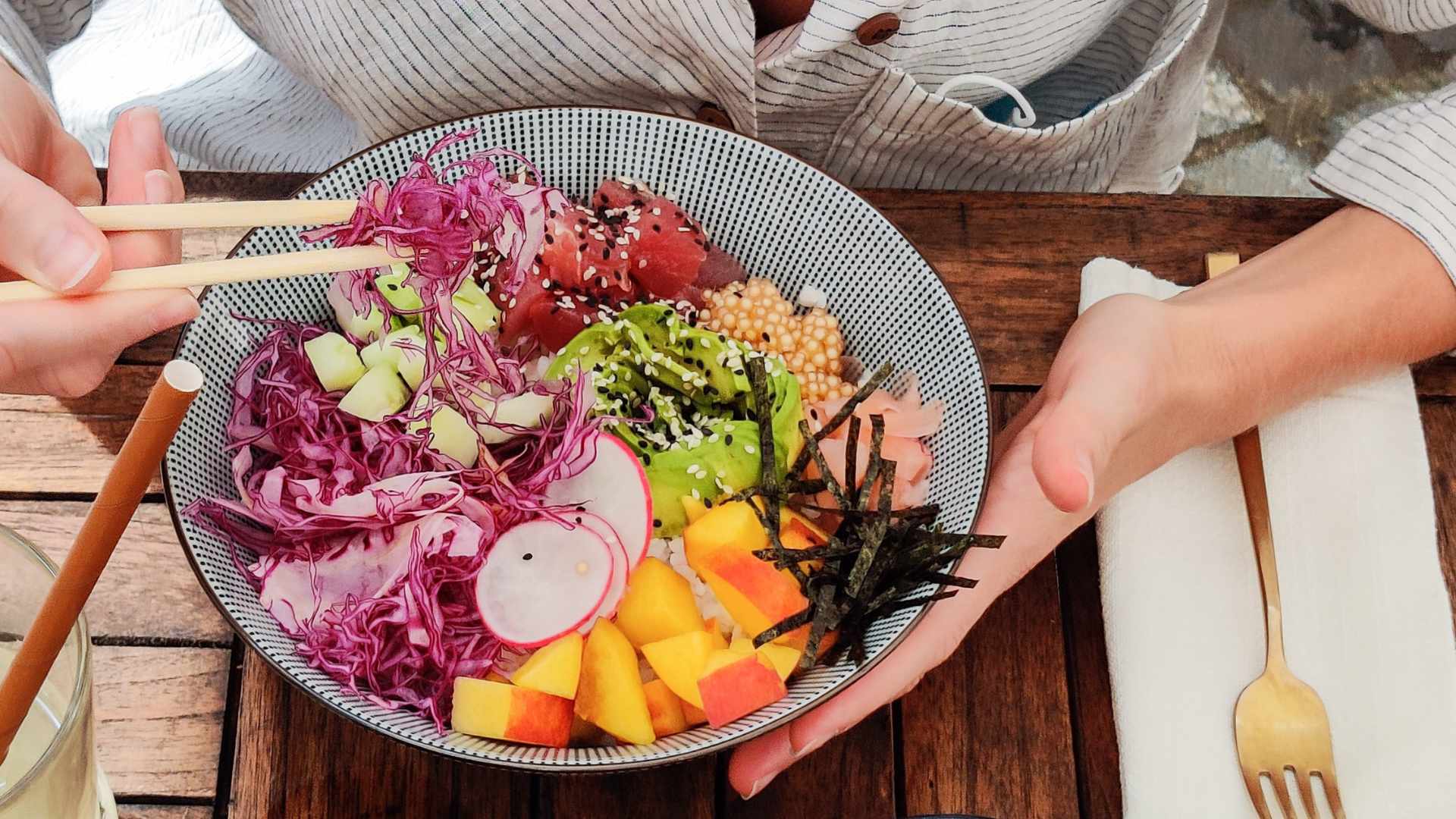 Woman eats a sushi bowl filled with fresh vegetables